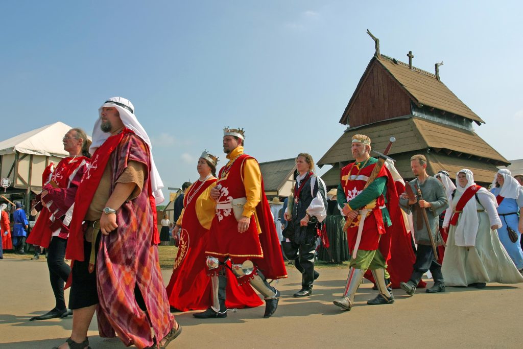 A royal procession passing by a stave church
